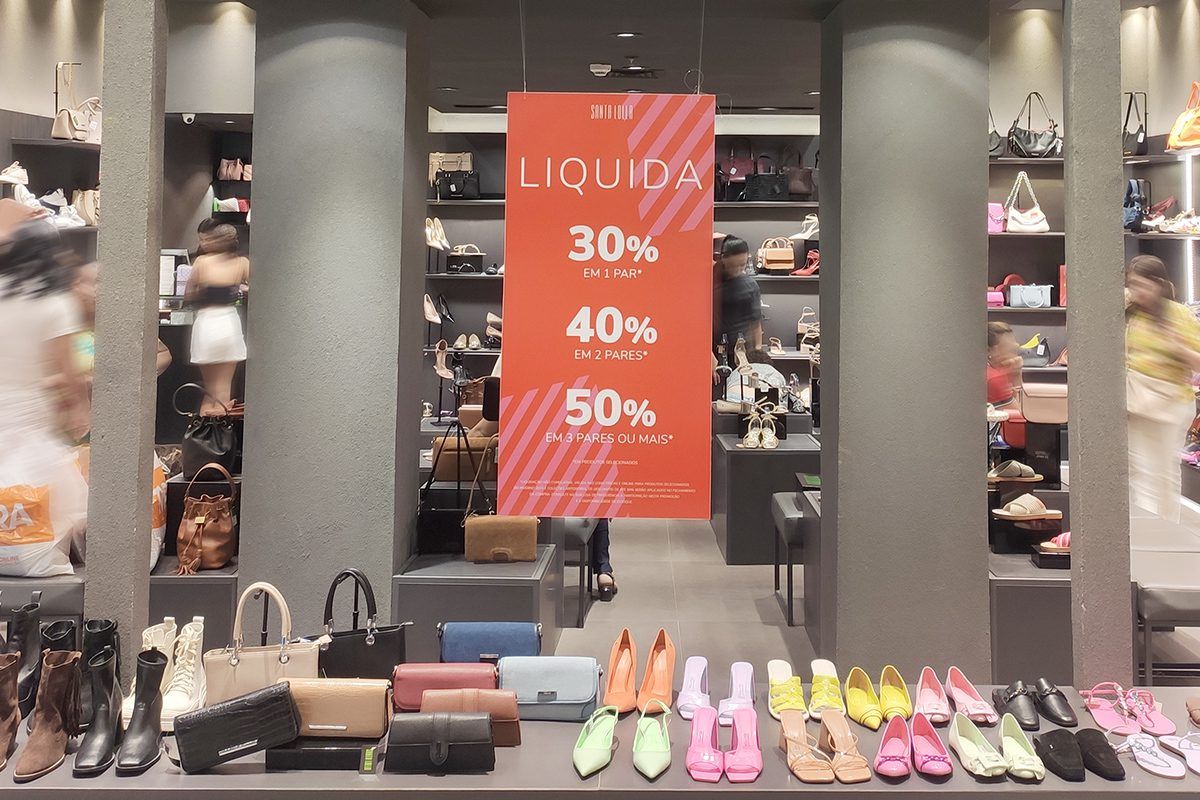 Imagem com calçados e bolsas expostas em vitrine de loja do Shopping Jardins com banner informando os descontos progressivos de 30, 40 e 50%