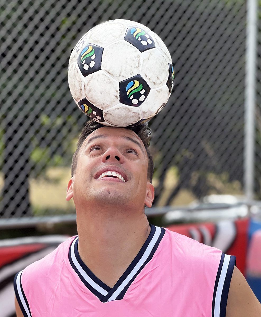 Imagem do atleta Diego Freestyle vestindo regata rosa, com bola na cabeça, demonstrando sua habilidade