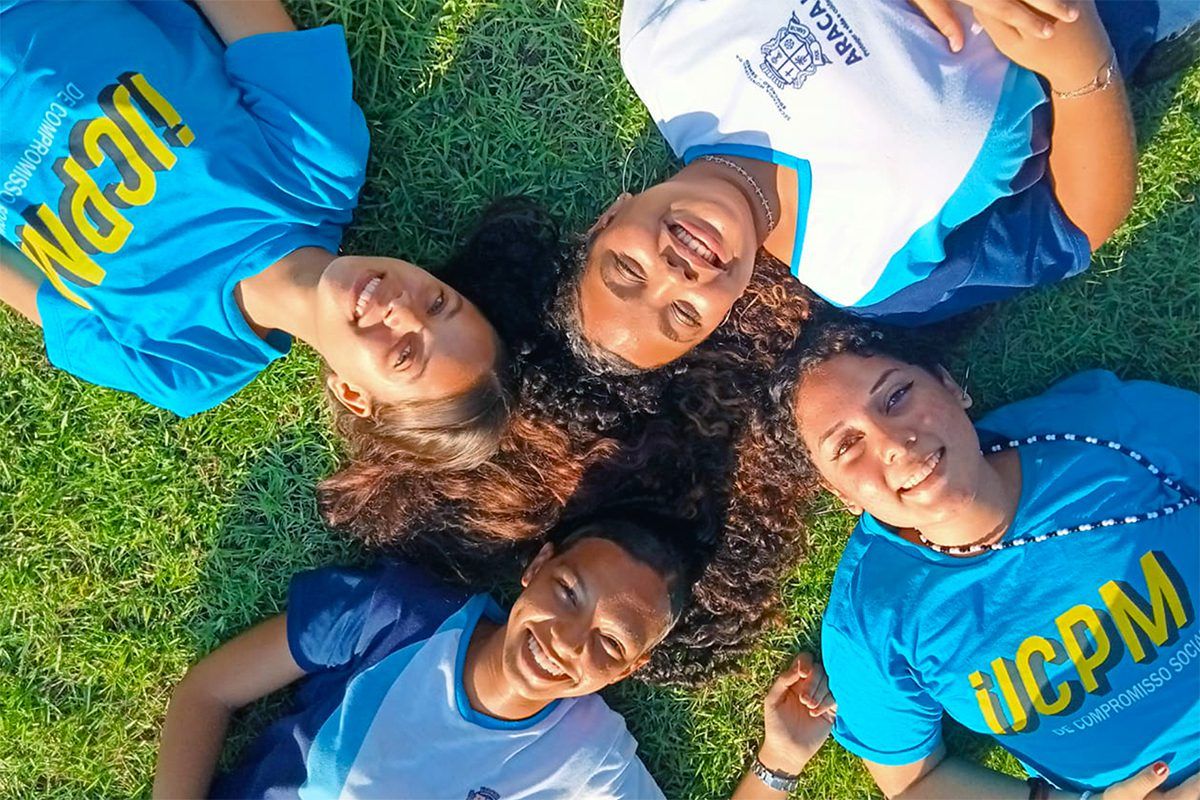 Imagem de quatro jovens deitadas na grama olhando para a câmera