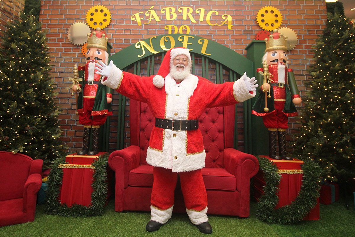 Imagem do Papai Noel em pé e de braços abertos em frente ao trono dele no Shopping Jardins